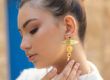 Femme portant une boucle d'oreille pendante en or de Sosol and Sea