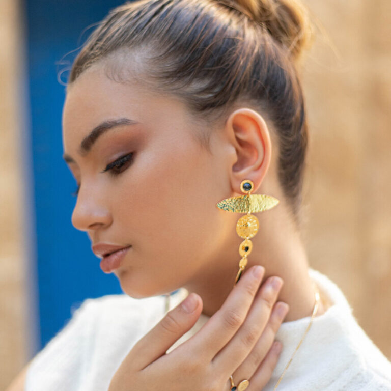 Femme portant une boucle d'oreille pendante en or de Sosol and Sea