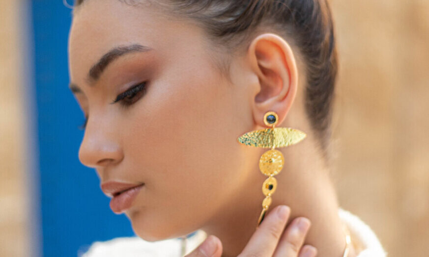 Femme portant une boucle d'oreille pendante en or de Sosol and Sea