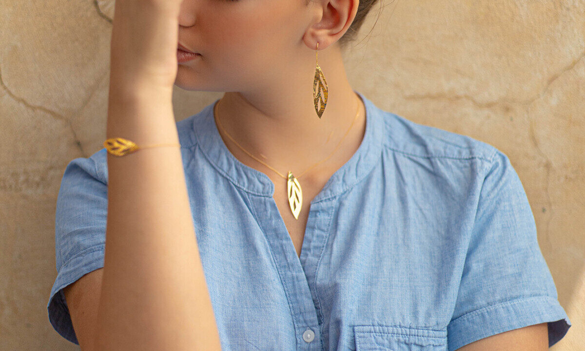 Femme portant un bracelet en or, un collier en or et des boucles d'oreilles pendantes en or Sosol and Sea