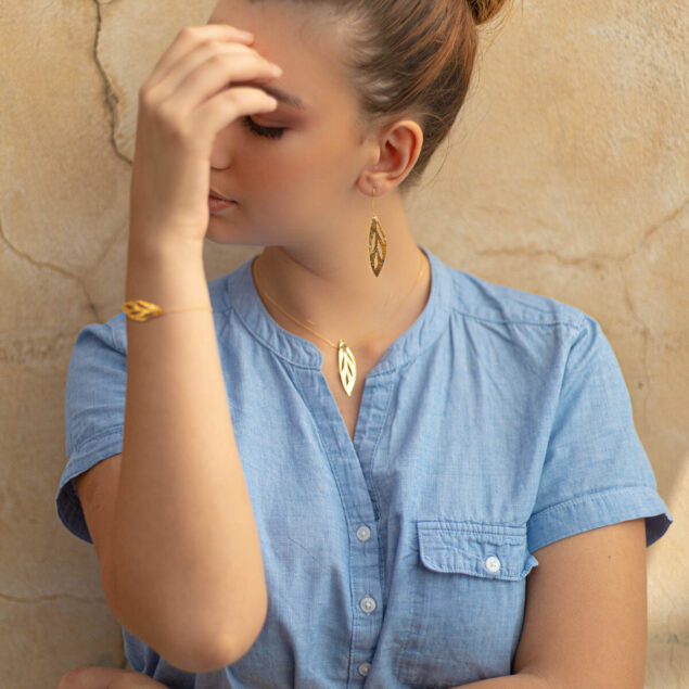 Femme portant un bracelet en or, un collier en or et des boucles d'oreilles pendantes en or Sosol and Sea