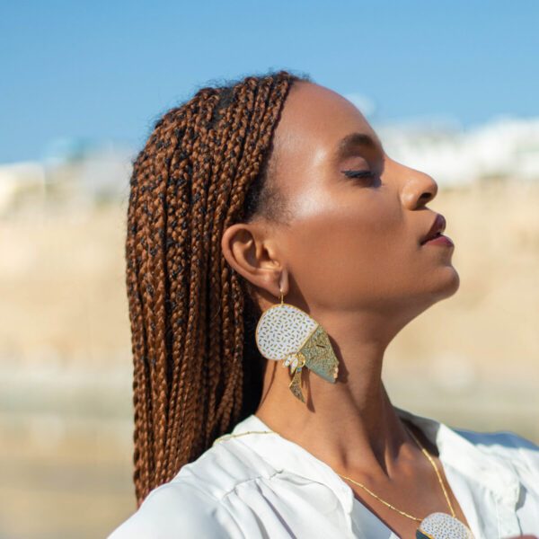 Mannequin portant une boucle d'oreille en or représentant le visage d'une femme africaine