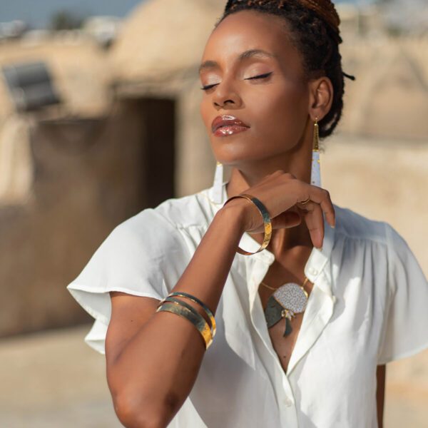 Mannequin portant des bracelets en or, des boucles d'oreilles triangles et un collier sautoir de Sosol and Sea