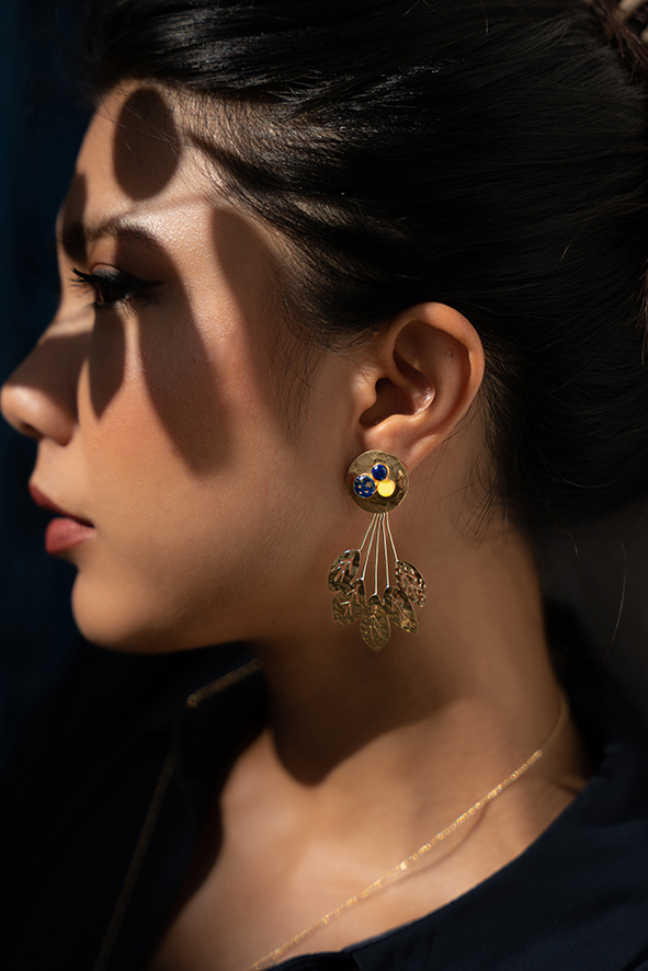 Mannequin portant des boucles d'oreilles pendantes en or martelé rondes et un design de feuille